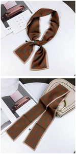 Detail of a brown and turquoise silk scarf tied on a bag with geometric pattern
