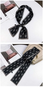 Detail of long black silk twilly scarf with white geometric print tied on handbag