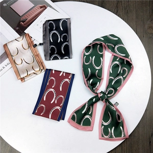 Flat lay of elegant horseshoe pattern silk scarves on a white tray over wood flooring