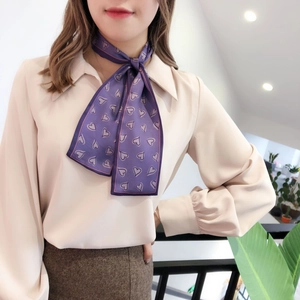 Détail d'un foulard en soie violet à motifs de cœurs noué avec élégance sur un mannequin