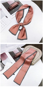 Pink twilly silk scarf with zigzag edges shown tied on a beige leather handbag handle
