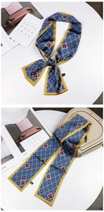 Detail of navy and yellow silk scarf with geometric patterns tied on a handbag handle