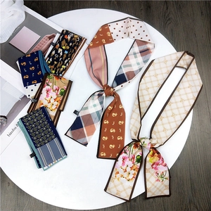 Assorted elegant double-sided silk scarves with floral and geometric prints on a tray