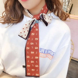 Red and white polka dot silk scarf with cat patterns worn by a model as a trendy necktie