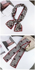 Detail of a beige silk-feel twilly scarf with geometric star patterns tied on a handbag