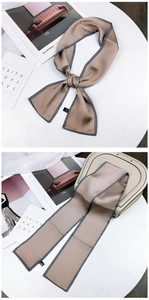 Detail view of champagne satin skinny scarf with geometric edges tied on a handbag