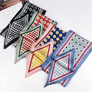 Close-up of assorted polka dot silk scarves in four colorways on white surface