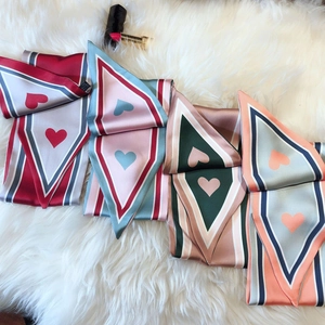 Detail of silk-feel scarves with geometric heart patterns on soft plush background