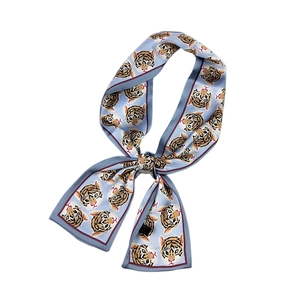 Light blue twilly scarf with cartoon tiger print and red border tied in a bow