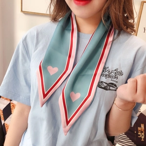 Detail of light blue skinny silk scarf with pink heart prints and colorful striped edges