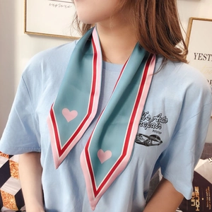 Detail of blue and pink silk scarf with heart patterns worn on a casual lettered t-shirt