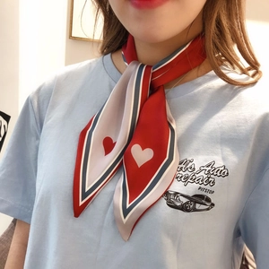 Detail of striped silk scarf with red hearts tied around neck on a light blue t-shirt