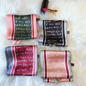 Flat lay of four satin scarves with artistic script on plush background for accessories