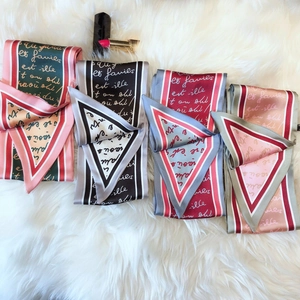 Flat lay of four colorful narrow silk scarves with elegant French script and lipstick detail