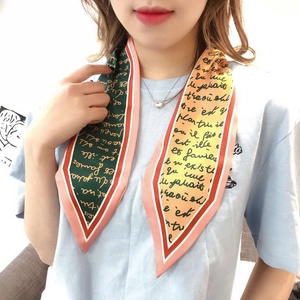 Close-up of a color-block silk scarf with French script lettering on a blue T-shirt