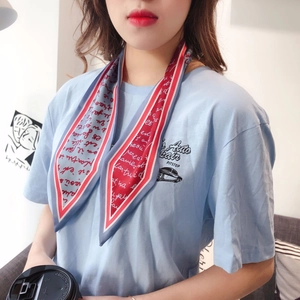 Detail of printed light blue neck scarf with red trim styled on a casual blue T-shirt