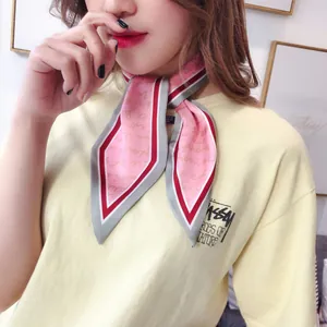 Close-up of pink silk neck scarf with elegant script and colorful decorative borders