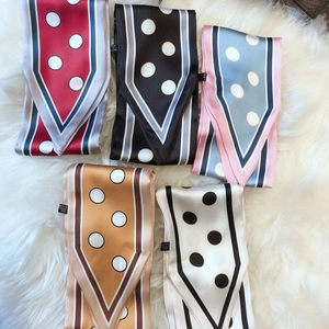 Polka dot silk-feel skinny scarves in five colors displayed on white plush background