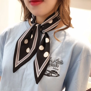 Detailed view of polka dot silk scarf with striped edges tied elegantly on neck