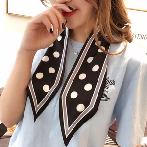 Detailed view of polka dot silk scarf tied around neck with classic black and white pattern
