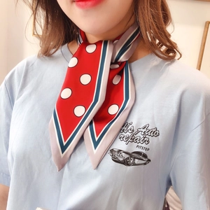 Detail of red polka dot silk scarf with navy trim tied in a stylish neck knot