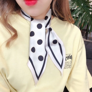 Close-up of white silk scarf with black polka dots tied elegantly on model neck