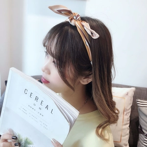 Detail of a geometric striped silk scarf headband with a knot bow on a warm background