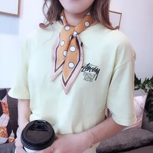 Detail of silk-texture orange polka dot scarf worn with a casual t-shirt in daily life
