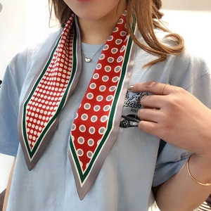 Close-up of red and green polka dot skinny silk scarf tied elegantly around the neck