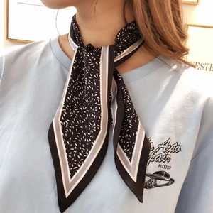 Detail of a black and white floral twilly scarf tied around the neck on a light blue tee