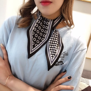 Close-up of stylish black and white polka dot silk scarf tied on a model's neck