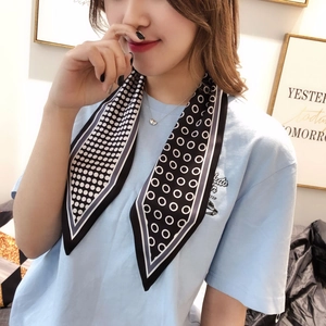 Detail of a geometric polka dot skinny silk scarf worn as a stylish neck tie accessory