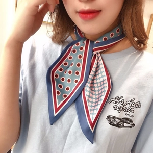 Close-up of narrow blue silk scarf with red polka dots tied around a woman's neck