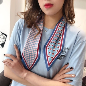 Detail of silk-feel scarf with blue and pink polka dots tied as a chic neck accessory
