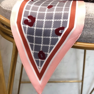 Detail of grey plaid silk twilly scarf with leopard print and orange edges hanging on a chair