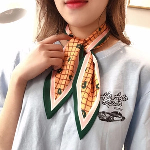 Close-up of orange plaid silk scarf with dark green edges and polka dots around the neck