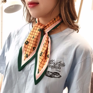Detail of yellow plaid twilly scarf with leopard print worn as an elegant neck accessory