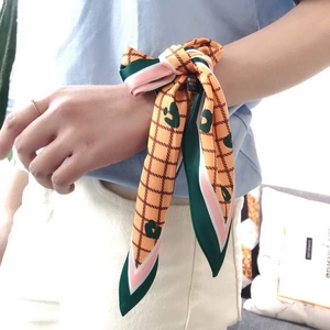 Detailed view of orange polyester scarf with heart patterns worn as a stylish wristband