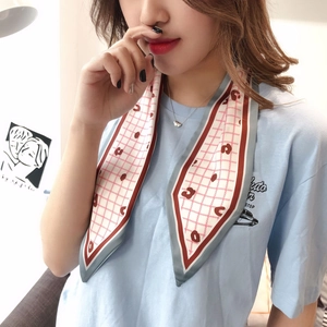 Detail of checkered narrow silk scarf with red heart motifs worn on model's neck