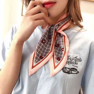 Detail of pink and orange geometric silk scarf tied as a stylish neck ribbon for women