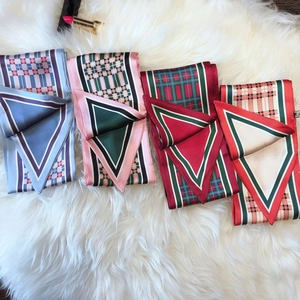Assorted plaid twilly silk scarves displayed on a soft white plush background texture
