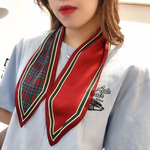 Detail of red and green plaid silk scarf tied as an elegant hair accessory for women