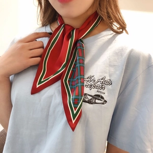 Detail of red pointed silk scarf with plaid pattern worn around neck by woman