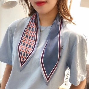 Close-up of a blue plaid skinny scarf tied elegantly on a light blue shirt neckline