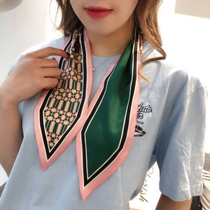 Detail of a geometric pattern twilly scarf tied on neck with green and pink accents