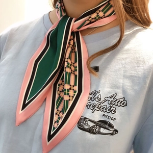 Detail of geometric plaid silk scarf tied on a retro T-shirt for a stylish outfit look