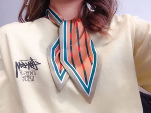 Close-up of elegant silk scarf with geometric buckle pattern tied around the neck