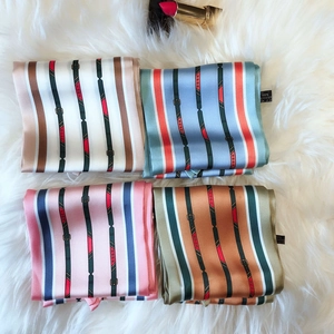 Flat lay of four colorful striped polyester silk scarves on a soft white plush background