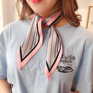 Close-up of a striped silk twilly scarf tied around neck over a blue graphic t-shirt
