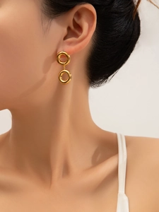 Macro detail of polished gold double circle drop earrings worn on a female model